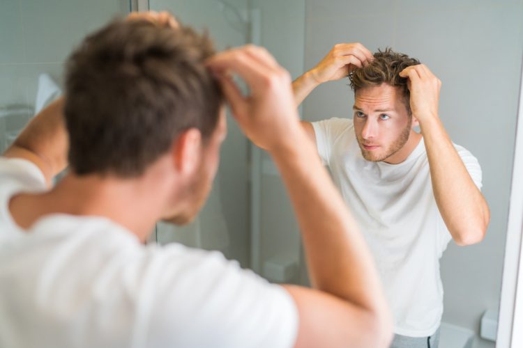 man looking at scalp to use thickenning shampoo