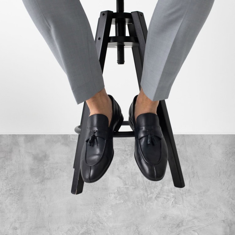 A persons legs in grey pants and black shoes.