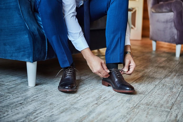 man tying black dress shoes