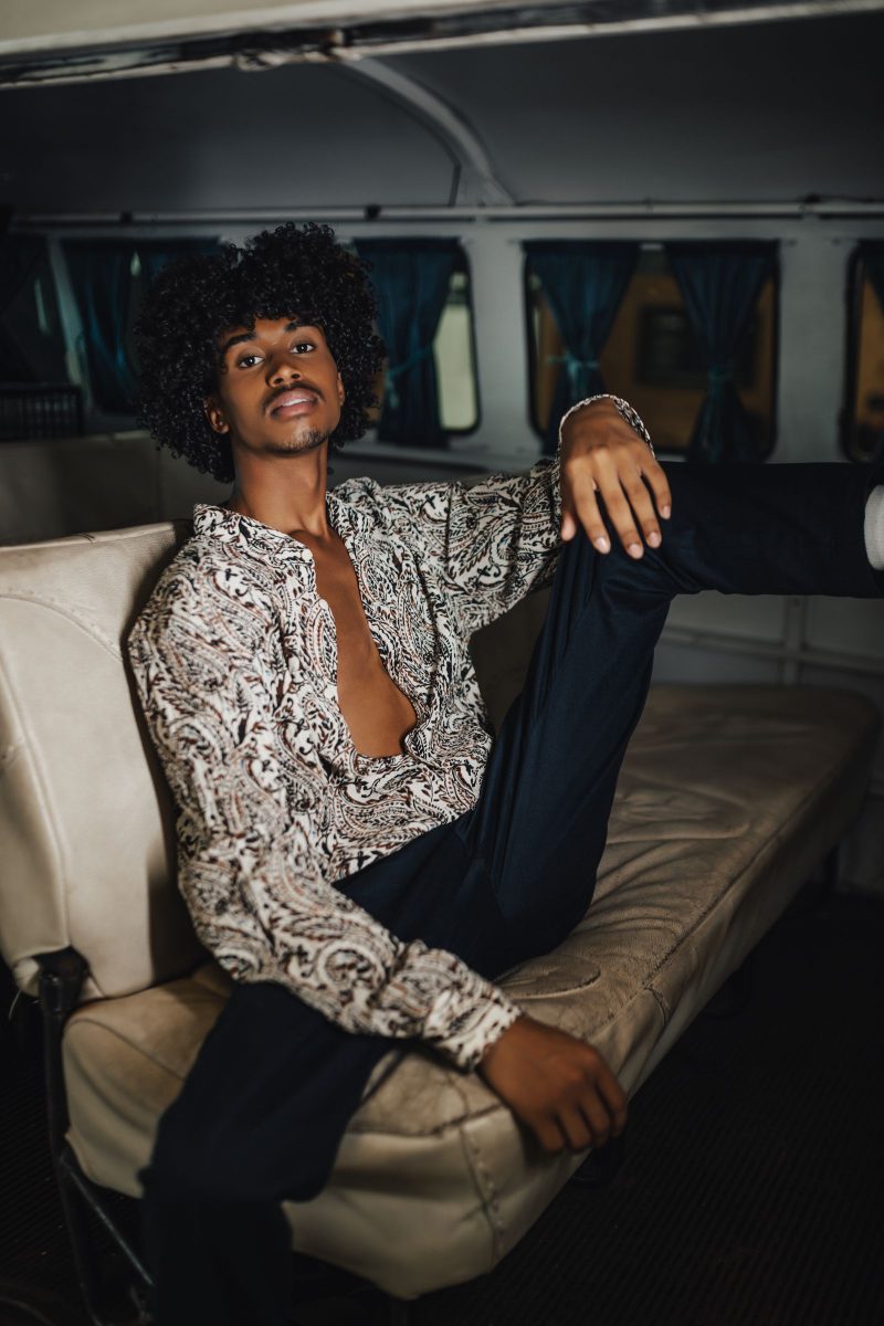 Man with curly hair in 70s vintage clothing in a retro interior