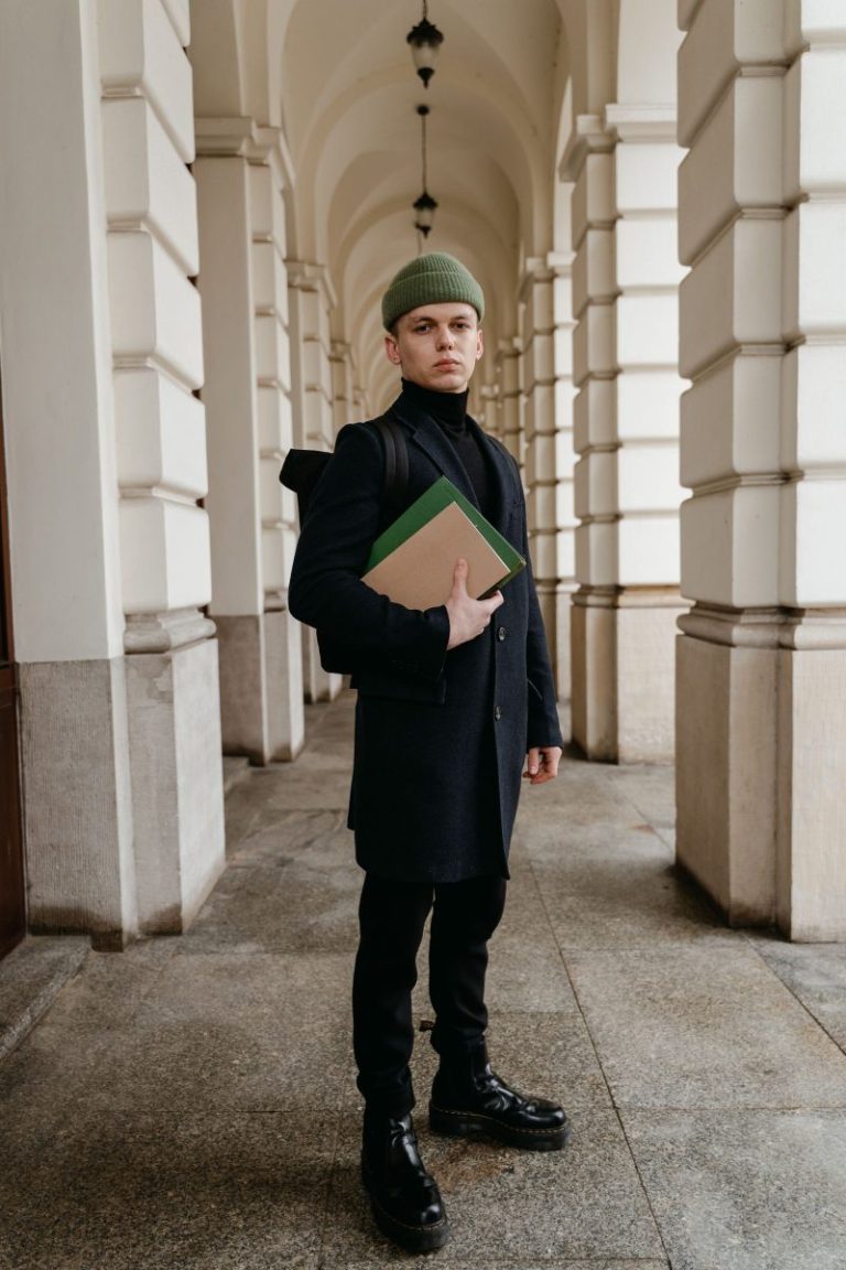 Young man in dark academia tailoring standing in a classic hallway