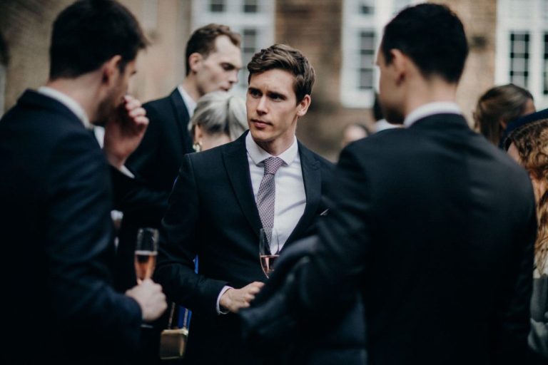 Well-dressed wedding guests in conversation outdoors