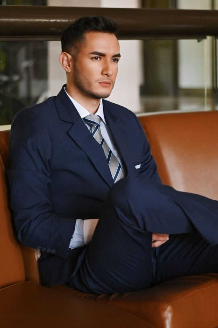Young man in a blue suit seated on a leather sofa before an interview