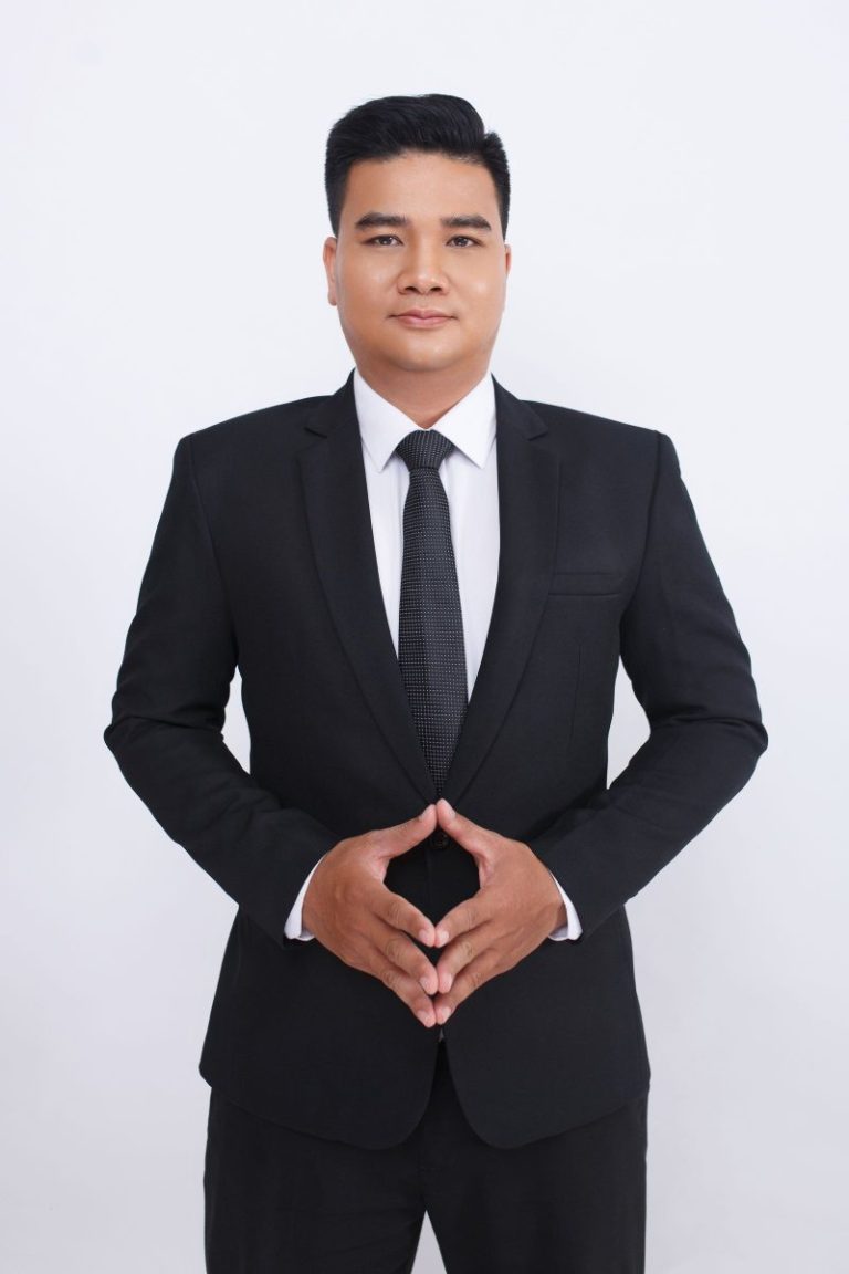 Man in a black suit standing composed by a dark door