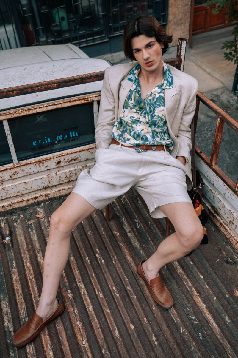 Man in a linen suit and floral shirt sitting on a pickup truck