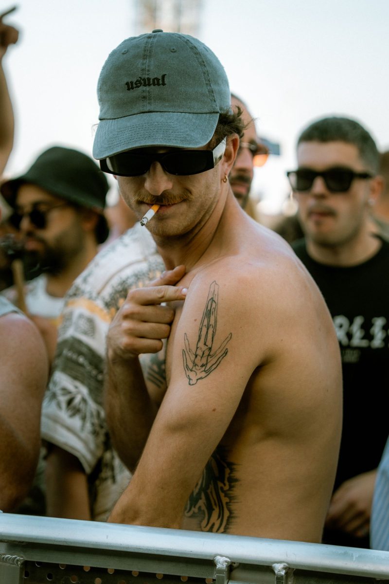 Man in a bucket hat and sunglasses at a concert with the crowd behind