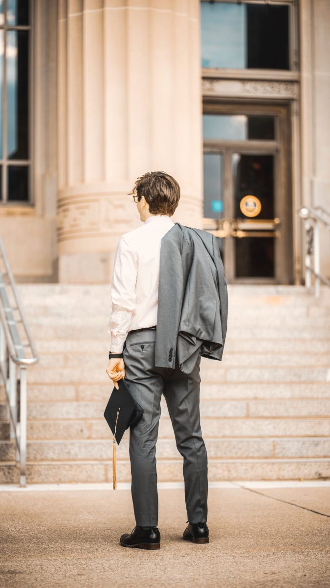 Man in a white shirt with his jacket over one arm on stone steps