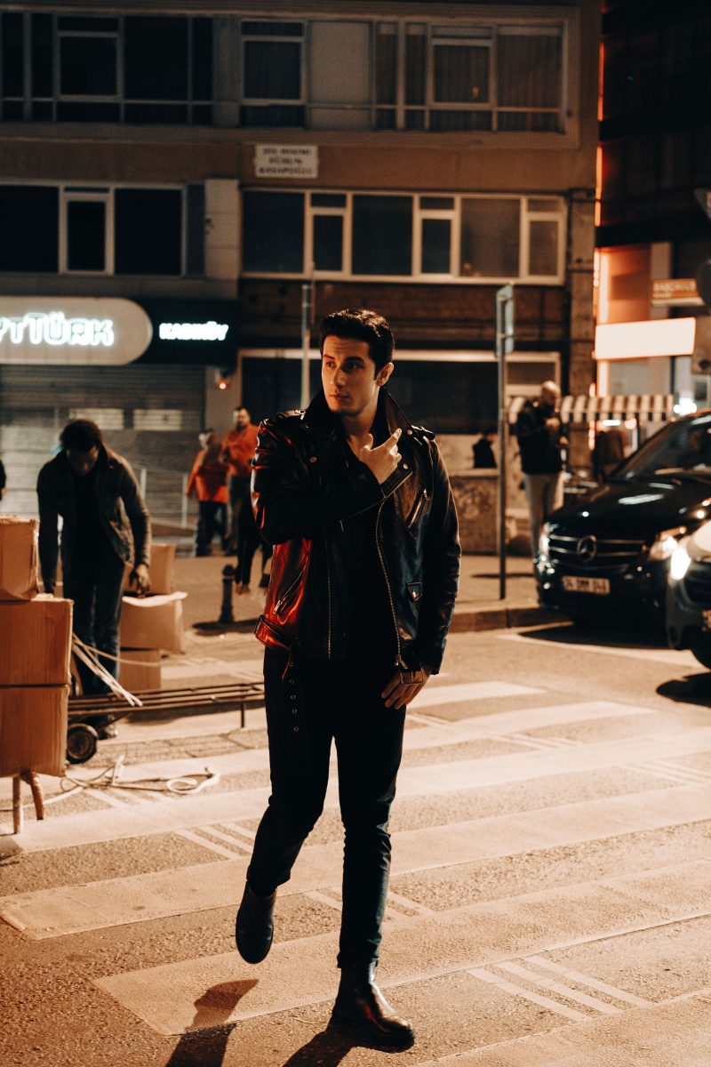 Man in a leather jacket on a city street at dusk