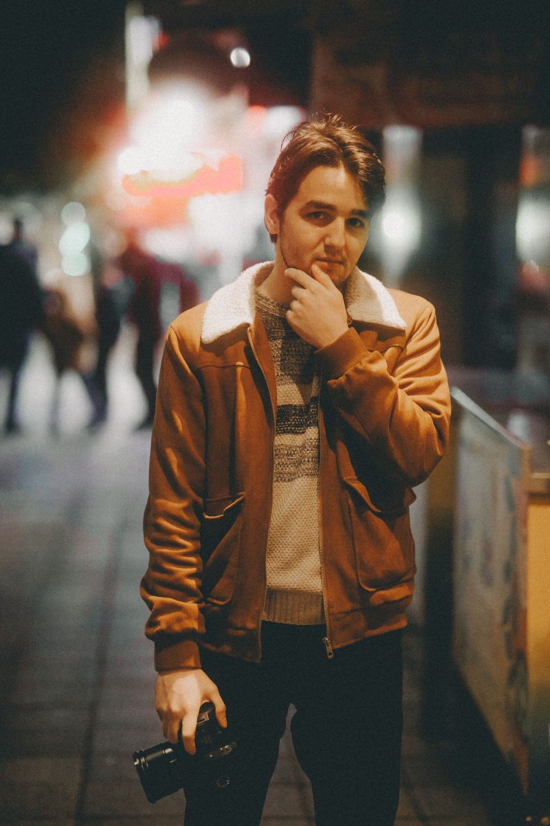 Man in a shearling-collar jacket on an evening street in warm light